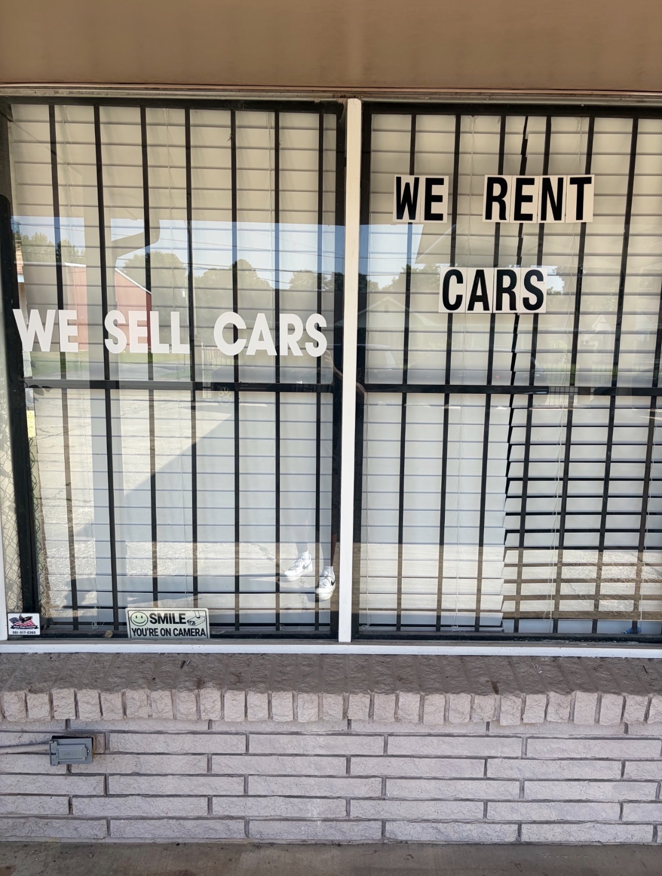 Storefront windows reading We Sell Cars and We Rent Cars